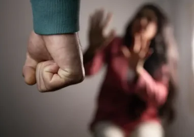 Homem com punho fechado ameaçando mulher assustada tentando se proteger.