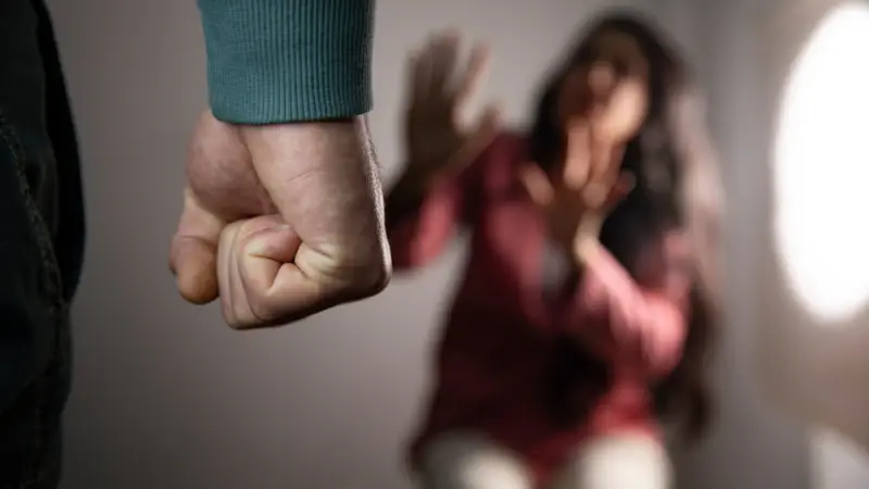 Homem com punho fechado ameaçando mulher assustada tentando se proteger.